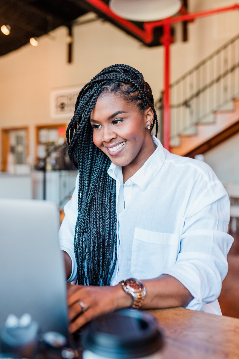 Alexis Campbell looking at a Macbook smiling 
