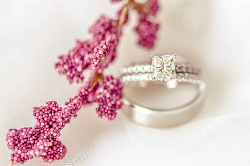 Close up of platinum wedding rings with dark pink flowers