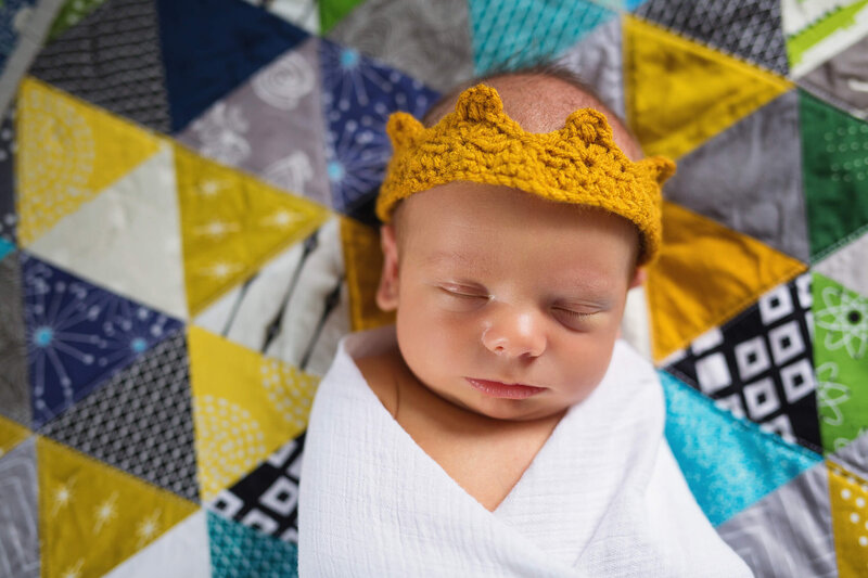 Newborn baby wears a yellow crown for a twin cities newborn photographer
