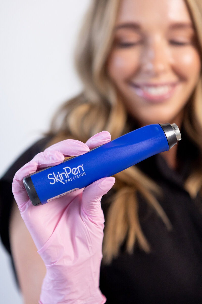 skin pen being held by hand with a pink latex glove