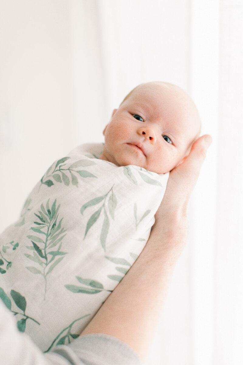 swaddled baby looking at camera by Chicago Newborn Photographer