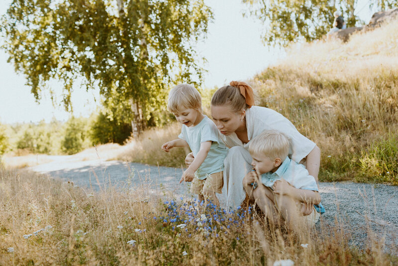 A mother and her two sons looking at wild flowers at a park in Helsinki in Finland