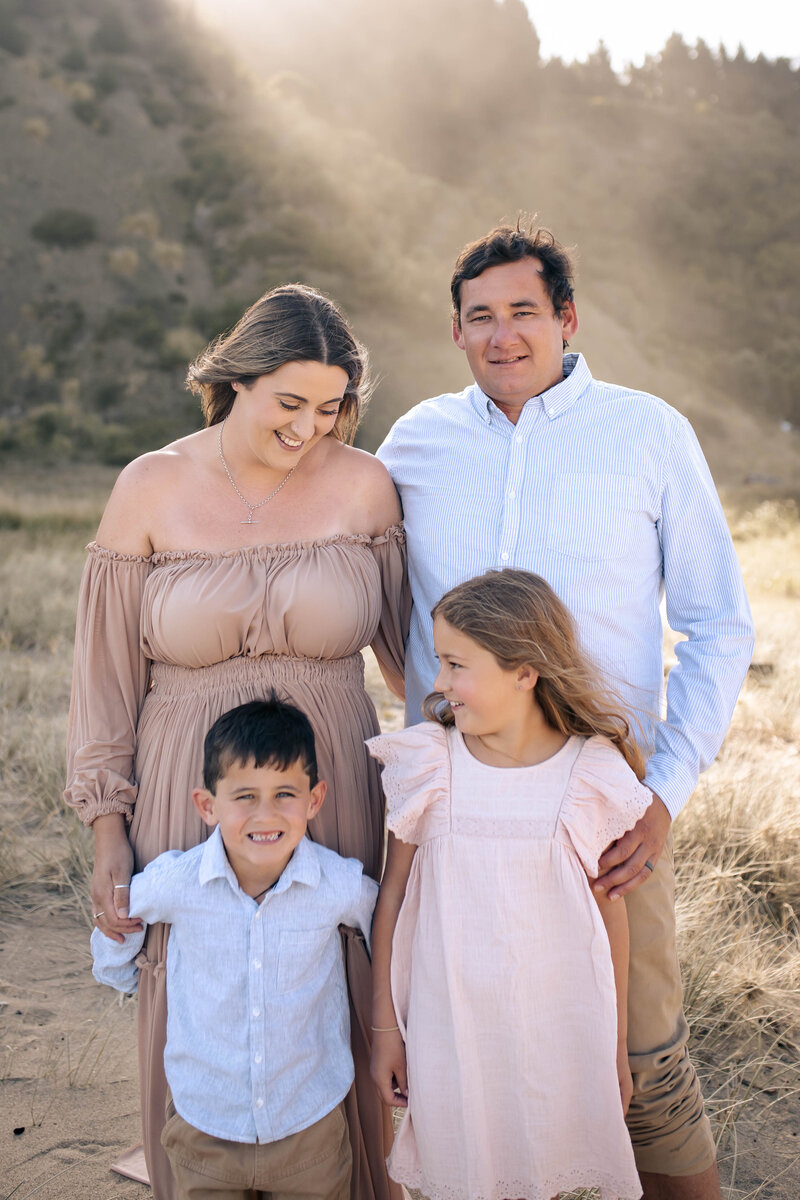 Family of four enjoying a playful moment on Waipatiki Beach, Hawke’s Bay – joyful family photography by a local Hawke’s Bay photographer, capturing cherished memories along the stunning coastline near Napier and Hastings