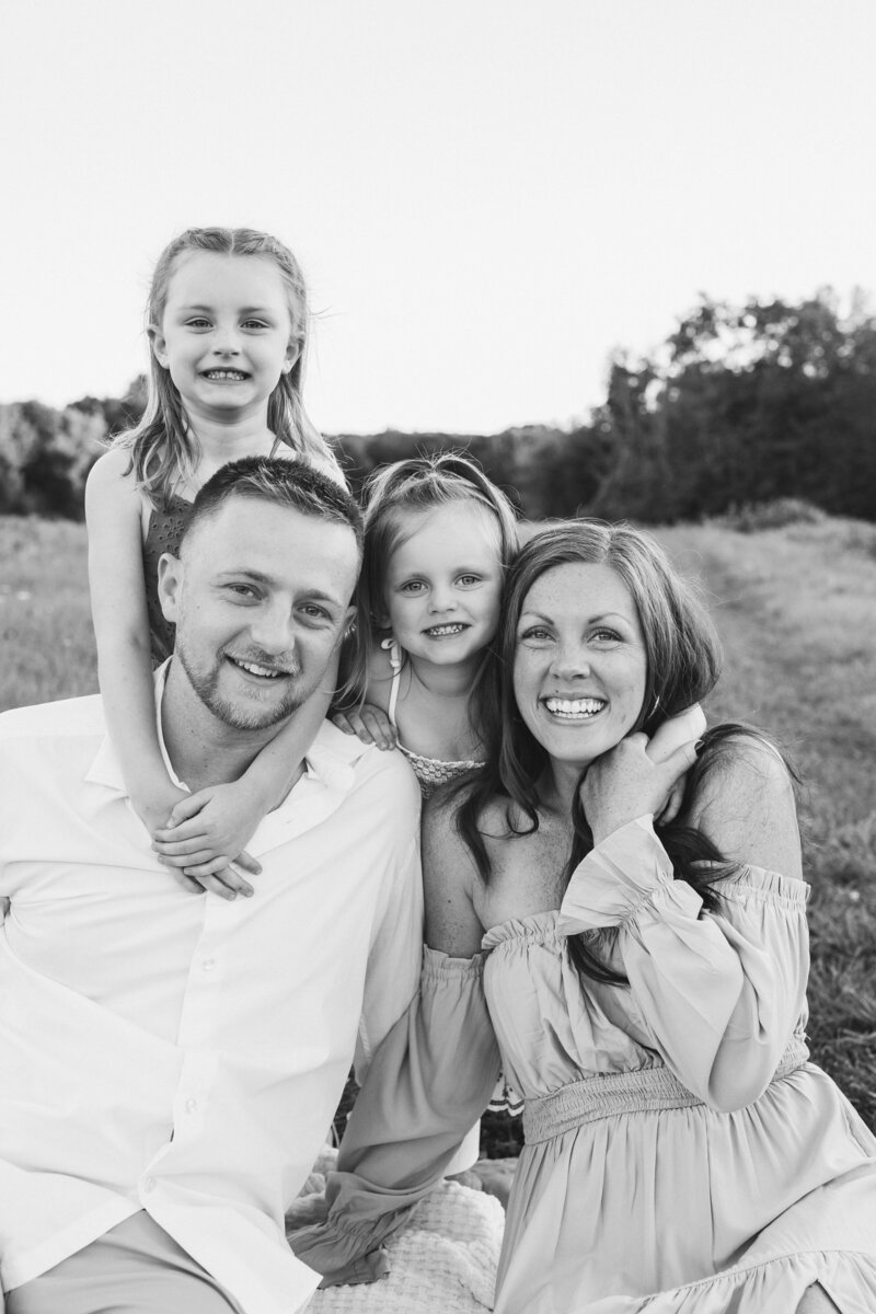 black ad white family photo of 2 kids and a wife and husband in a field
