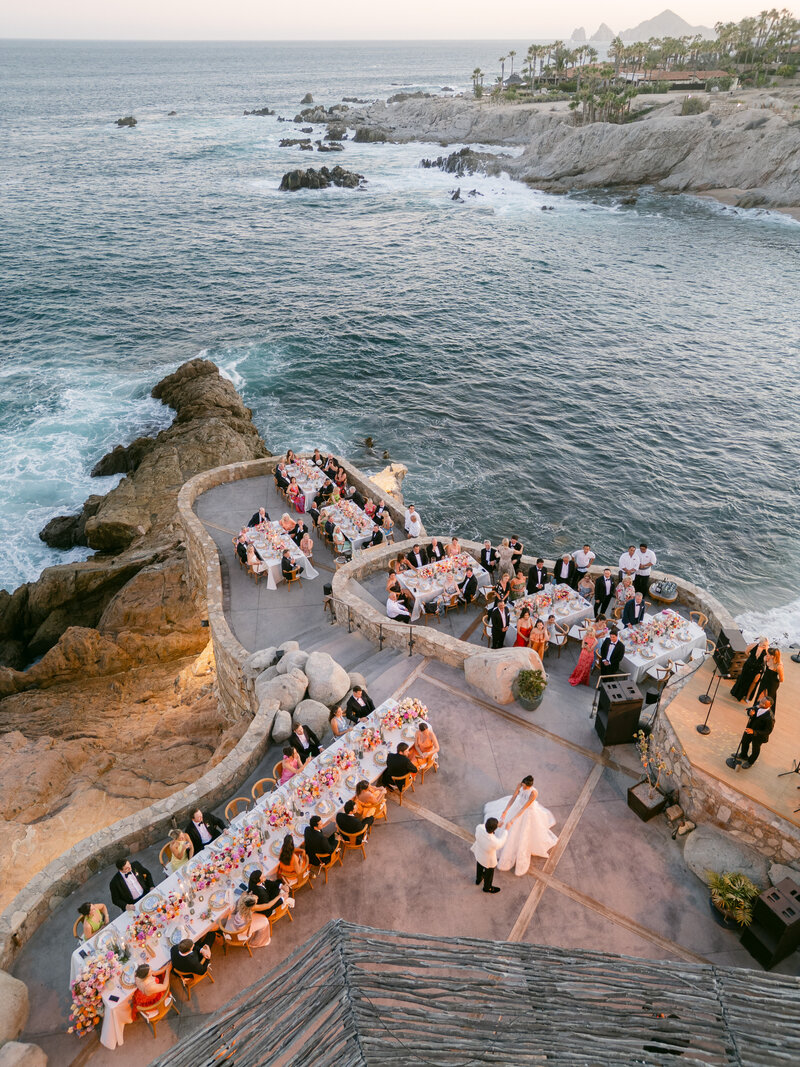 White wood wedding ceremony arbor covered with red and pink flowers