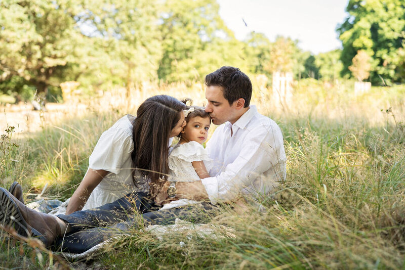 Couple kissing their daughter during photo shoot in Richmond Park