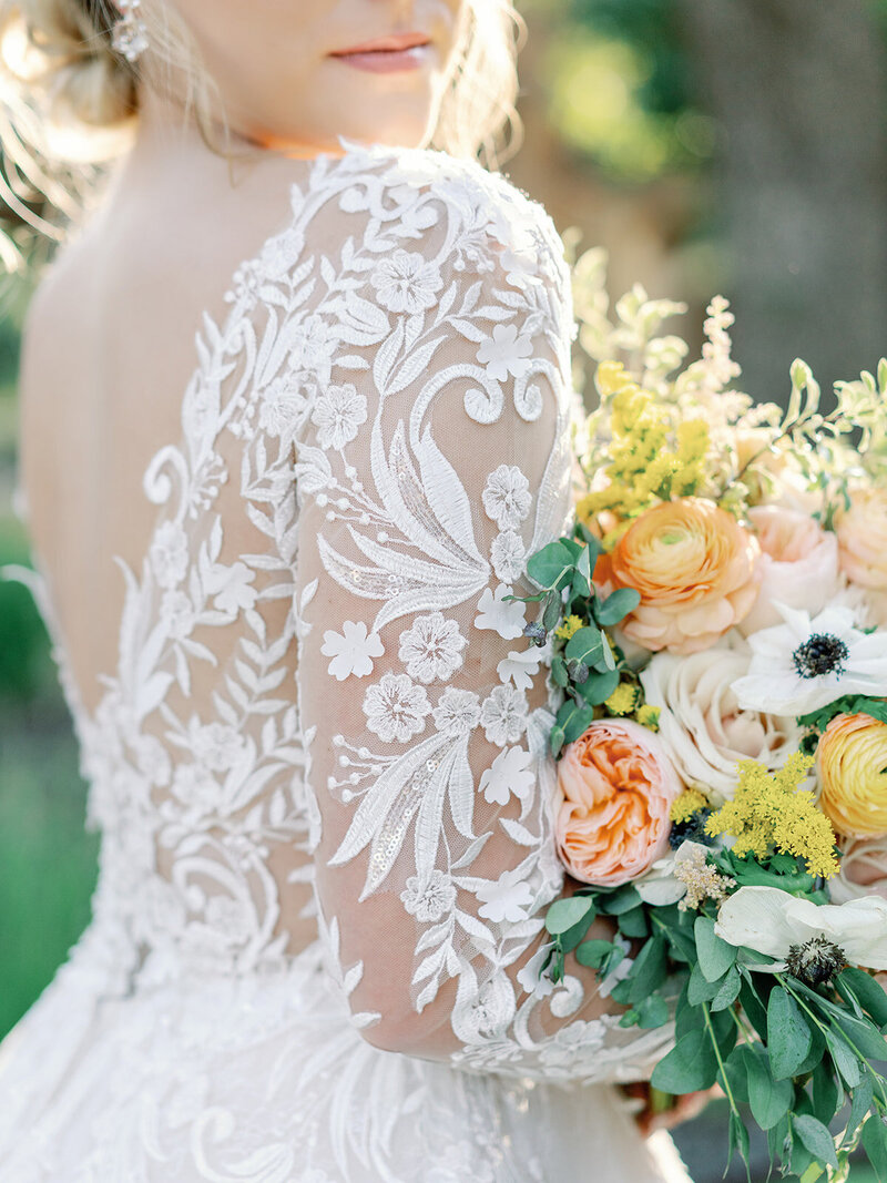 Bride holding her fall inspired wedding bouquet with cream and orange flowers