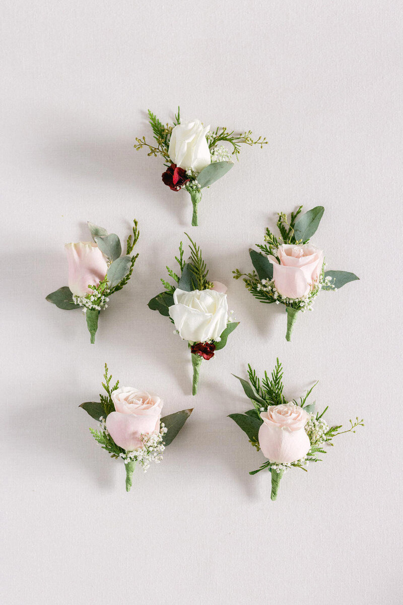 Capture the refined details of the groom's morning preparations with a stunning lay flat photograph of elegant boutonnières. A perfect inspiration for sophisticated wedding day accessories.
