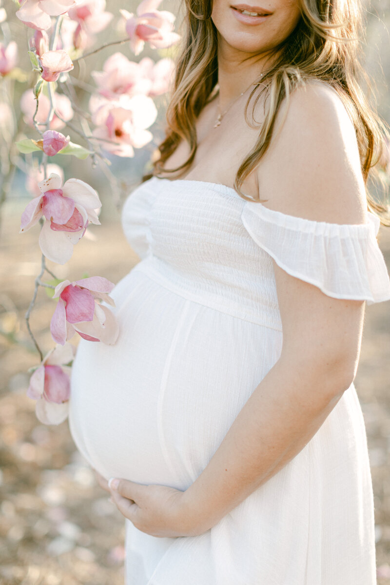 Pregnant woman embraces her belly during maternity photography session