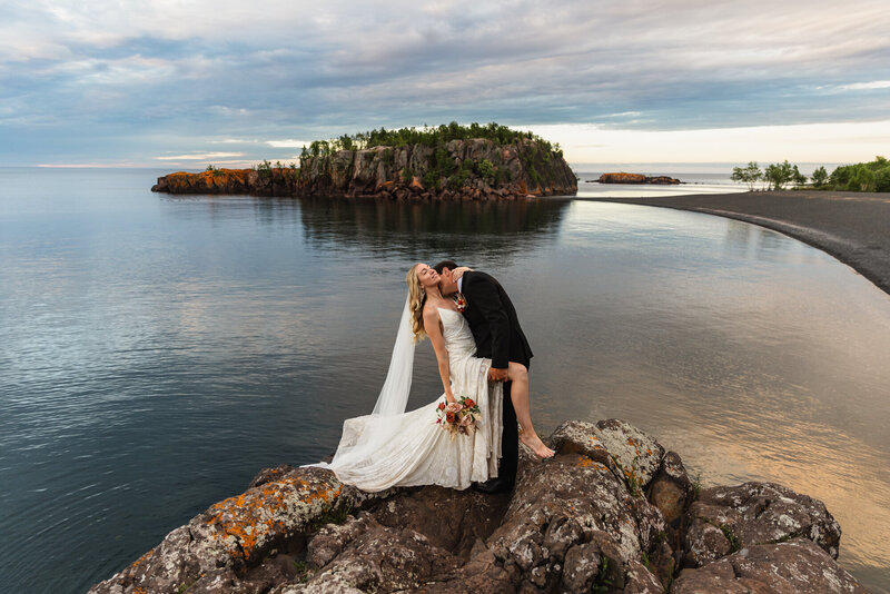 bride and groom kissing by river