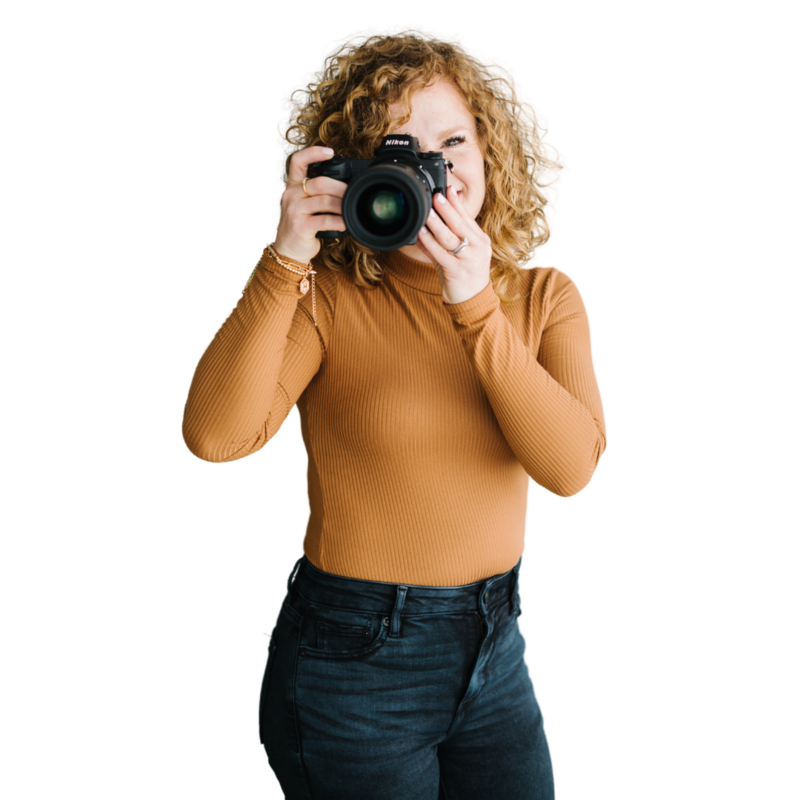 red headed woman holds a camera up to her face