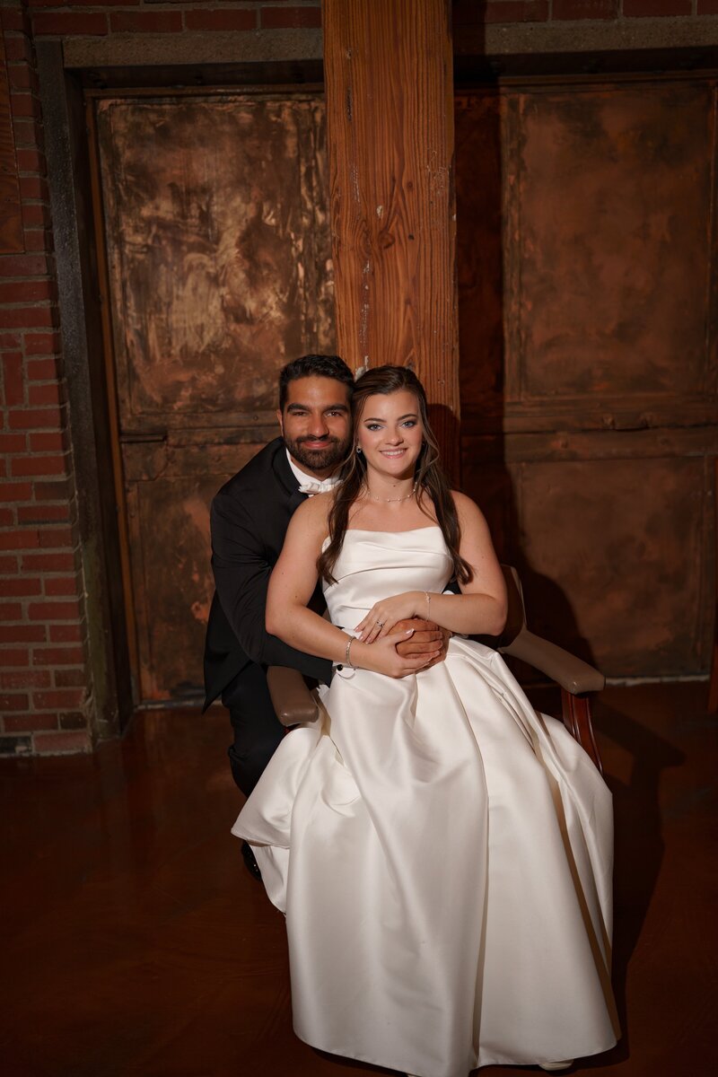 Bride and groom sitting together in front of rustic copper doors at Mill Top in Noblesville, Indiana