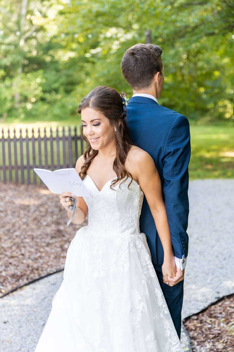 Bride and groom back to back with bride reading letter