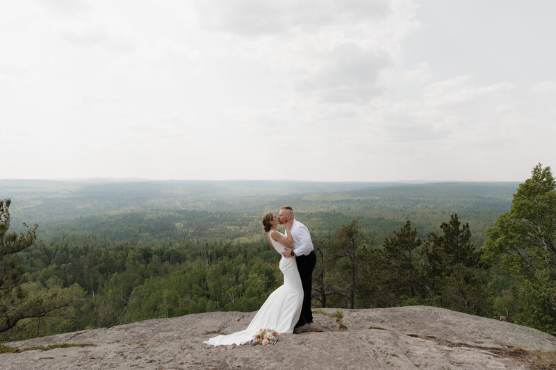 A newlywed couple kissing on a mountain overlook 