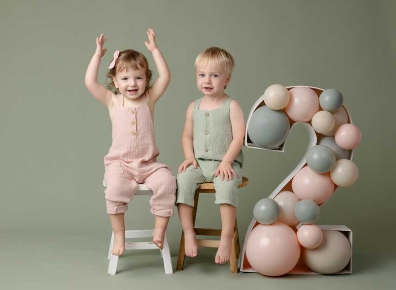 Boy and girl twins sitting on stool by #2 balloon filled marquee. Atlanta Children photography session was taken by Jenni Nikki Photography.