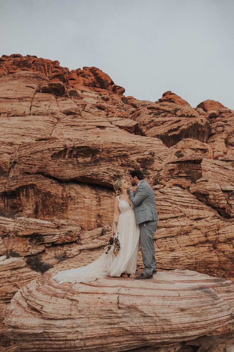 bride and groom kissing on rocks