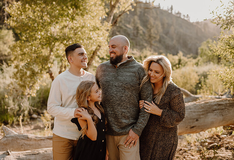 Family of four pose in front of small mountain along a river in Northern Colroado