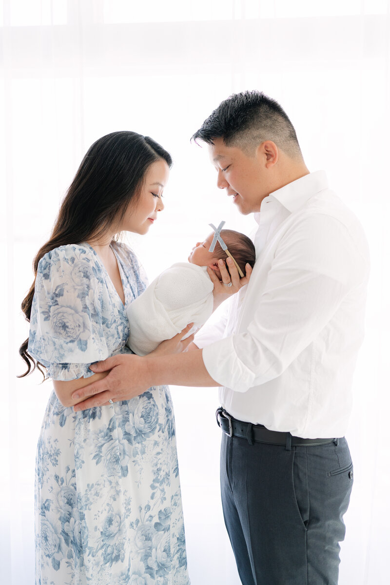 Colorado mom holding her newborn daughter being hugged by her husband during a studio photography session
