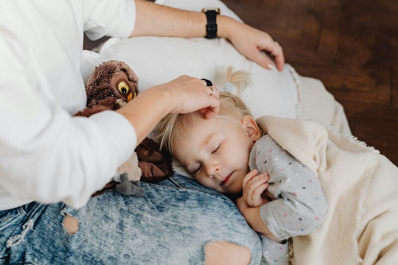 mom sitting with toddler while he sleeps