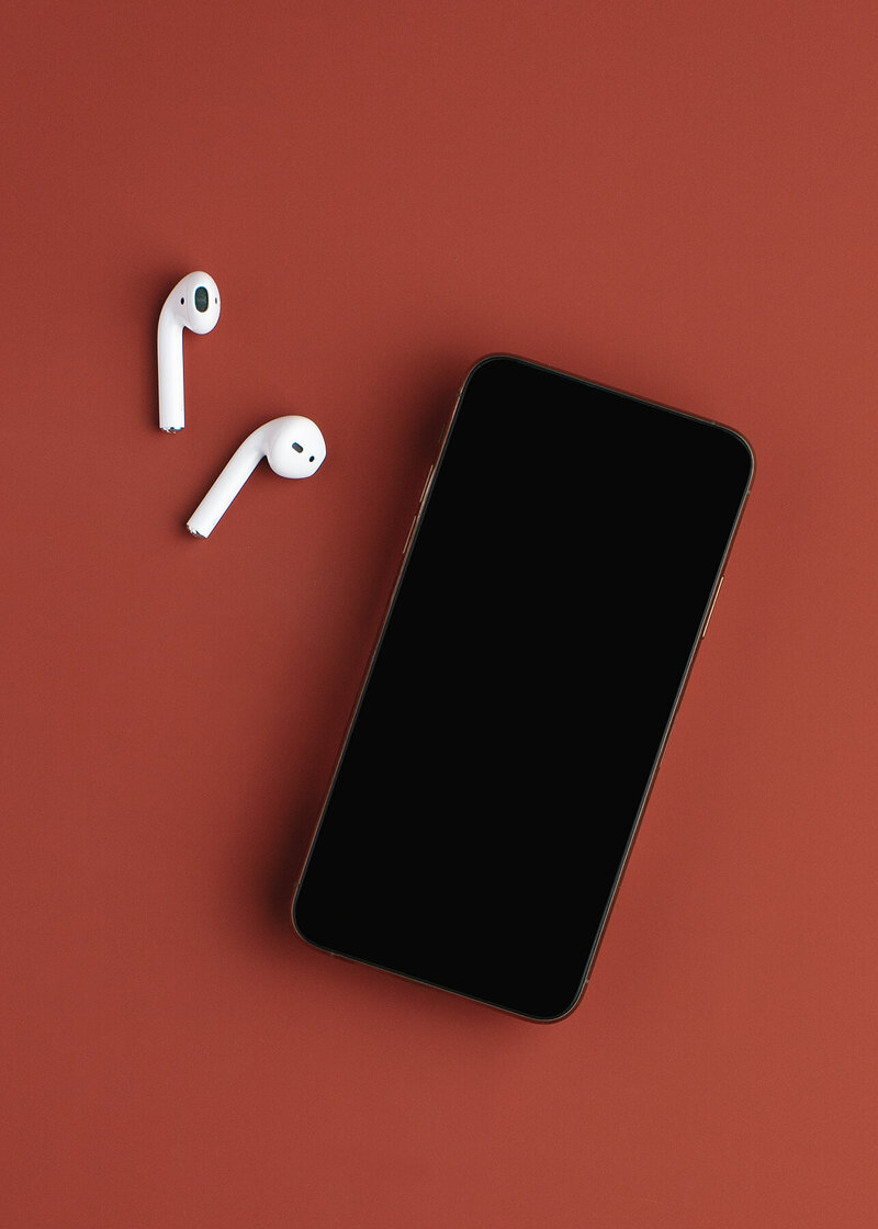Iphone and Airpods on a red table