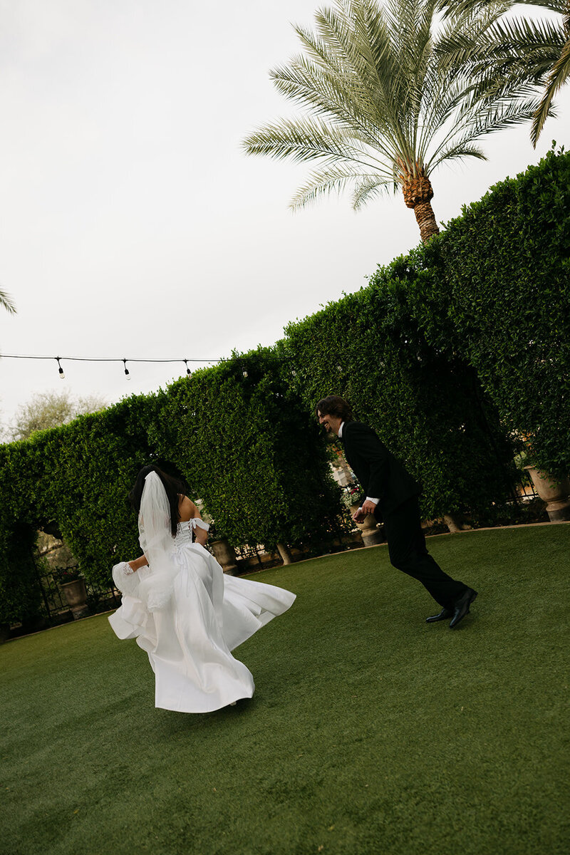 timeless wedding photo of bride and groom running around lawn