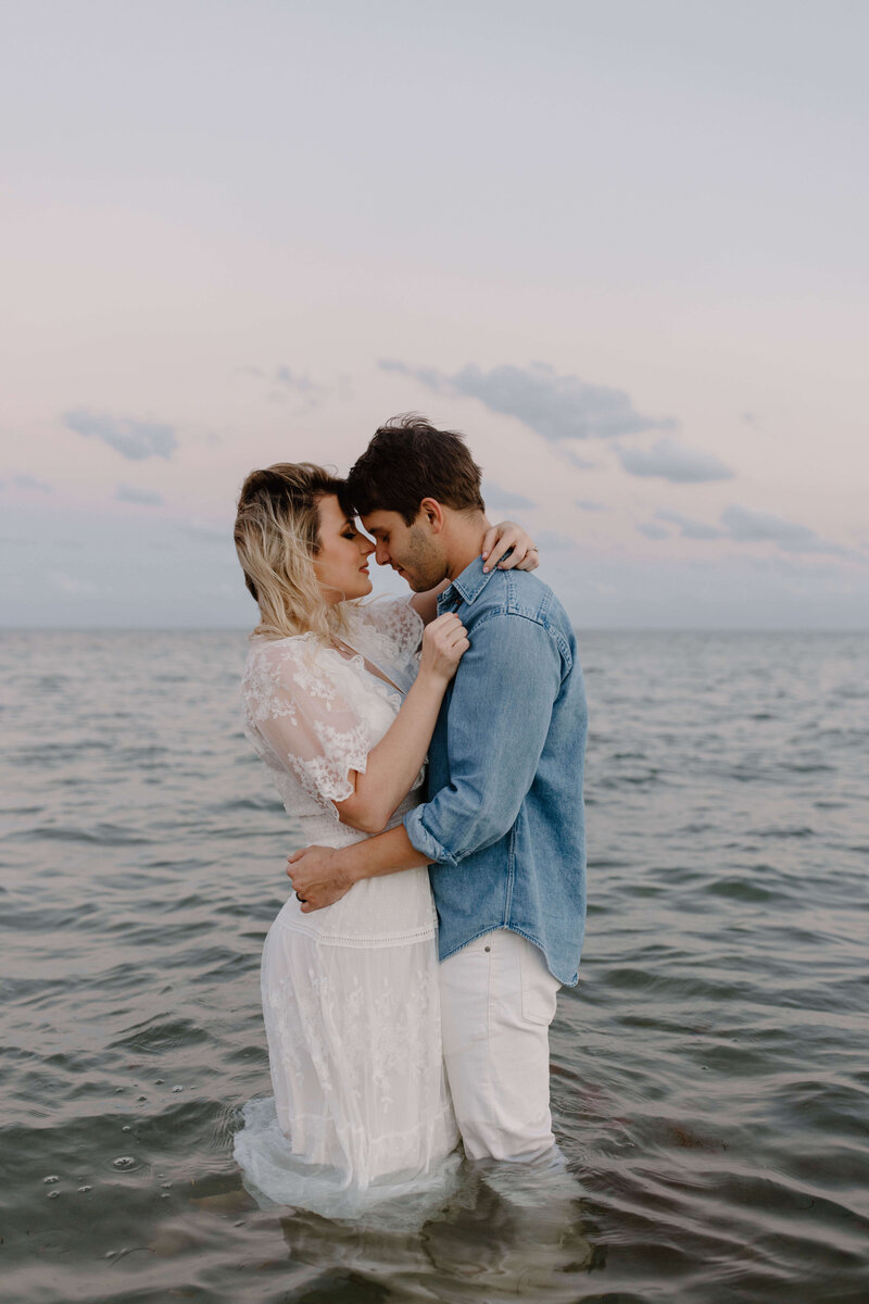 young and beautiful engaged couple kissing in water at rehoboth beach delaware at sunset photography