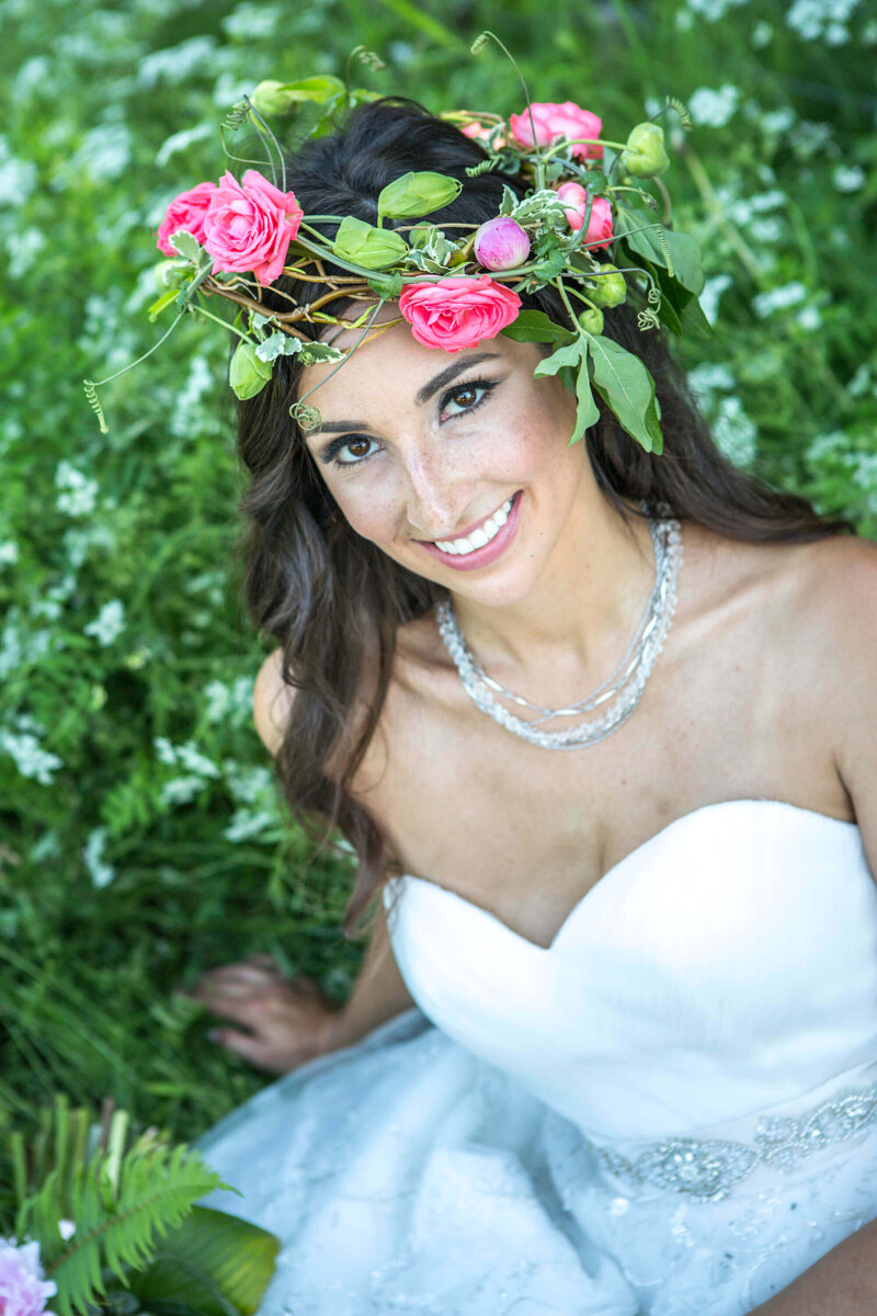 bride sitting in grass wearing flower crown