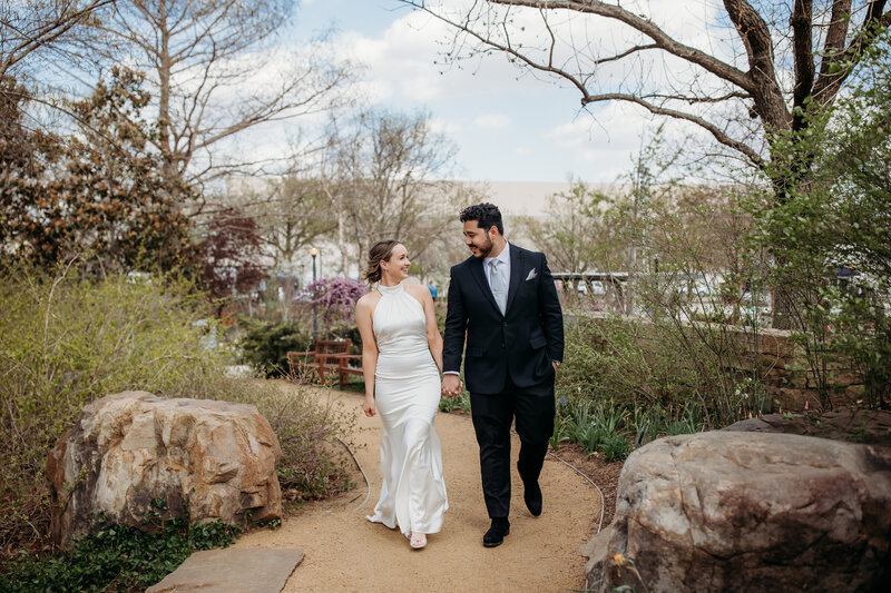 Bride and groom strolling through Myriad Gardens in Oklahoma City, sharing a smile and enjoying a peaceful moment post-ceremony