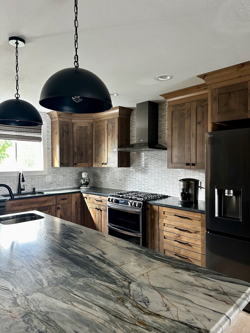 Kitchen with marble countertops, dramatic light fixtures and a deep blue island