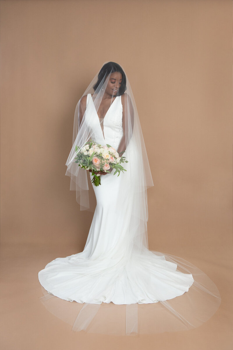 Bride wearing a cathedral length drop veil with blusher and holding a white and blush bouquet