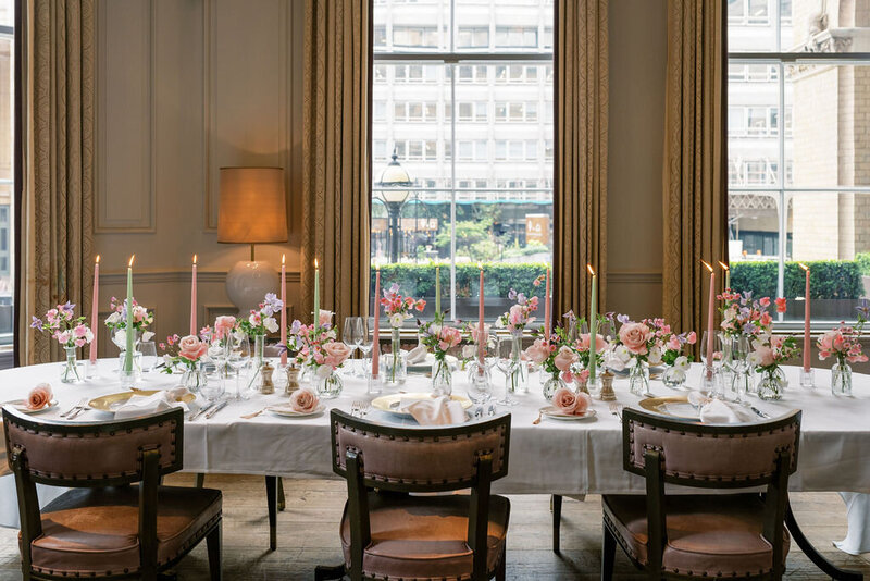 Elegant private dining setup at Langham London Hotel with a beautifully set table, pink floral arrangements, and candles in a sophisticated room.