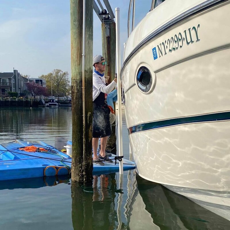 Worker cleaning the side of a yacht from
