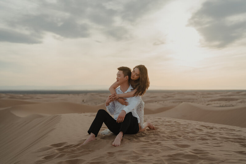 Intimate couple gazing at the sunset in the sand dunes