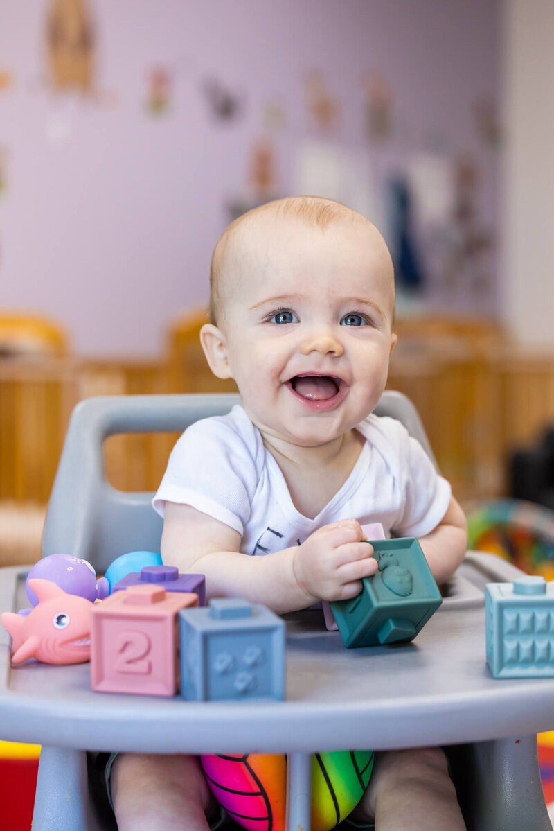 infant playing with blocks and smiling
