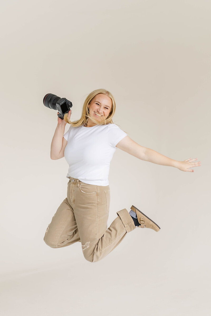 Jessica Nicole Photography jumping in the air smiling holding her camera ready to photograph your Colorado wedding.