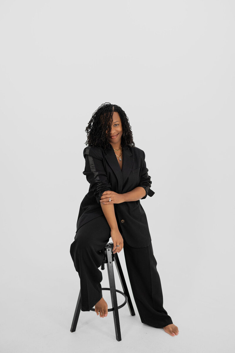 Meet your challenge host- Latesha—Your Marketing & Lead Generation Strategist. She's leaning against a wall in a brown body suit, slacks, hand in her pocket, apple watch, smiling with red lipstick on. 