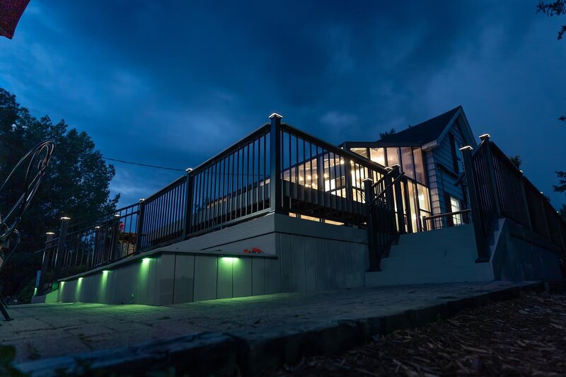 Low-angle view of a deck on the front of a local frozen yogurt shop with built-in planters and green LED lights, at nighttime. 