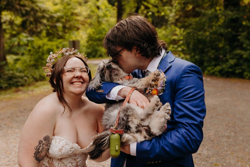 couple stands in midst of brush and tumbleweed smiling and embracing