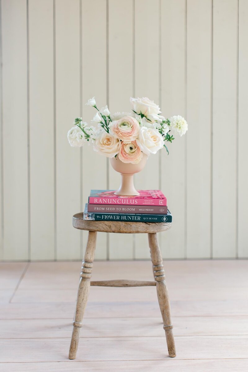 A tall gold stand of flowers with white hydrangeas, pink roses, white stocks and white peonies. Hanging jasmine trails with gold tea lights and dinner candles nestled at the base for this Cornwall wedding