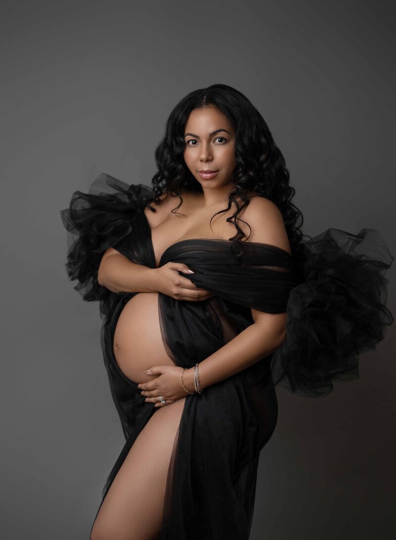 Mom holding baby bump dressed in black robe. Photo was taken by Jenni Nikki at her Atlanta Photo Studio that specialized in Maternity Photography.