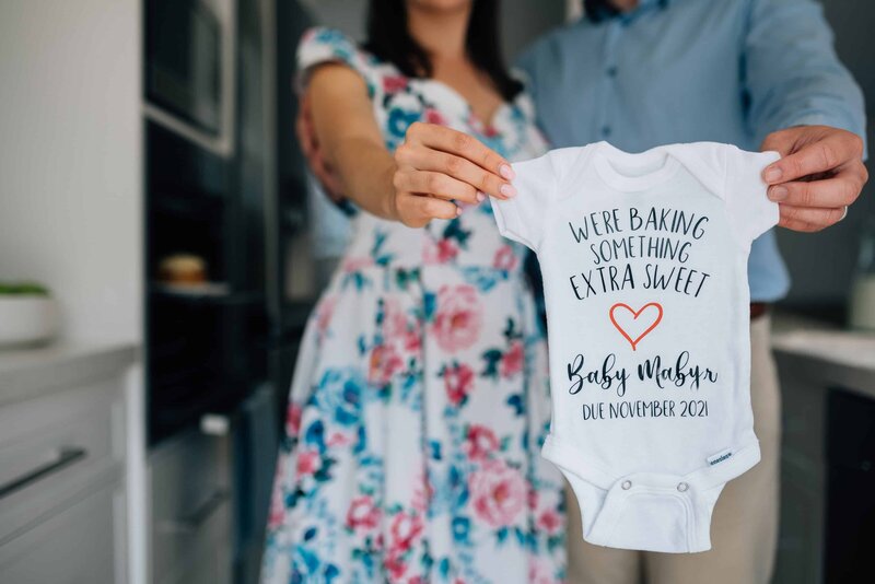 Man and woman holding out onside with text, announcing pregnancy.