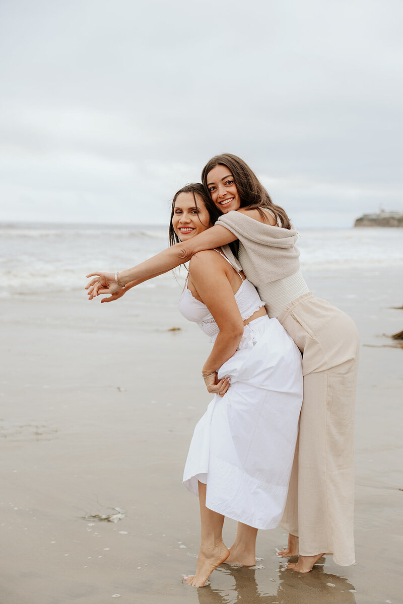 Picture of two girls on the beach smiling and looking at a camera