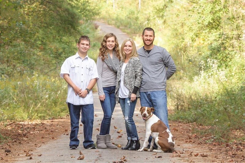 Family of four with the dog on a country road posing for their family portraits.