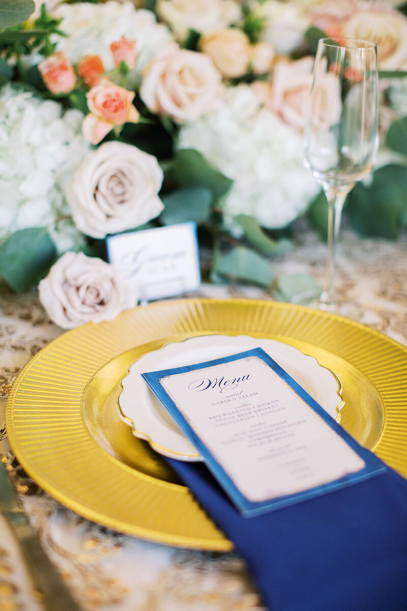 17-radiant-love-events-table-setting-closeup-gold-charger-navy-napkin-menu-floral-centerpiece-romantic-elegant-timeless