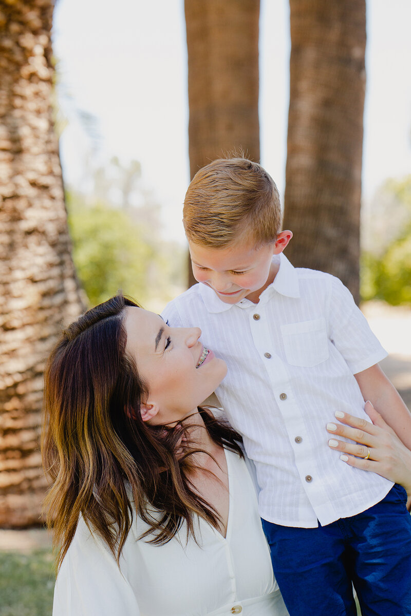 A small blonde boy cuddles up against his mother for a sweet moment