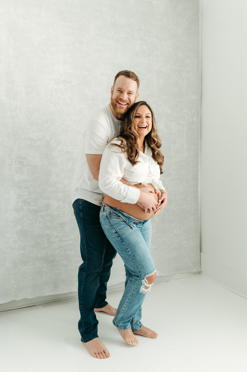 Maternity portrait of mum and dad in a studio in Atlanta. The mum is wearing white shirt and blue jeans.