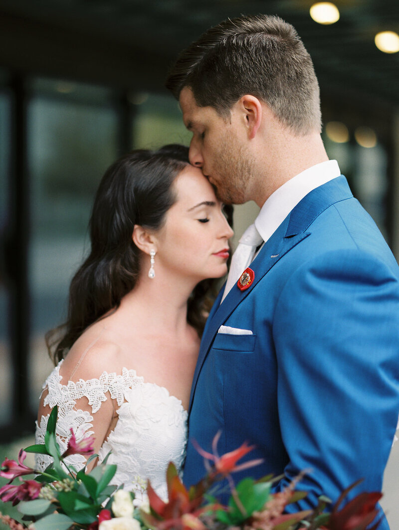 groom kissing his bride lovingly on the forehead