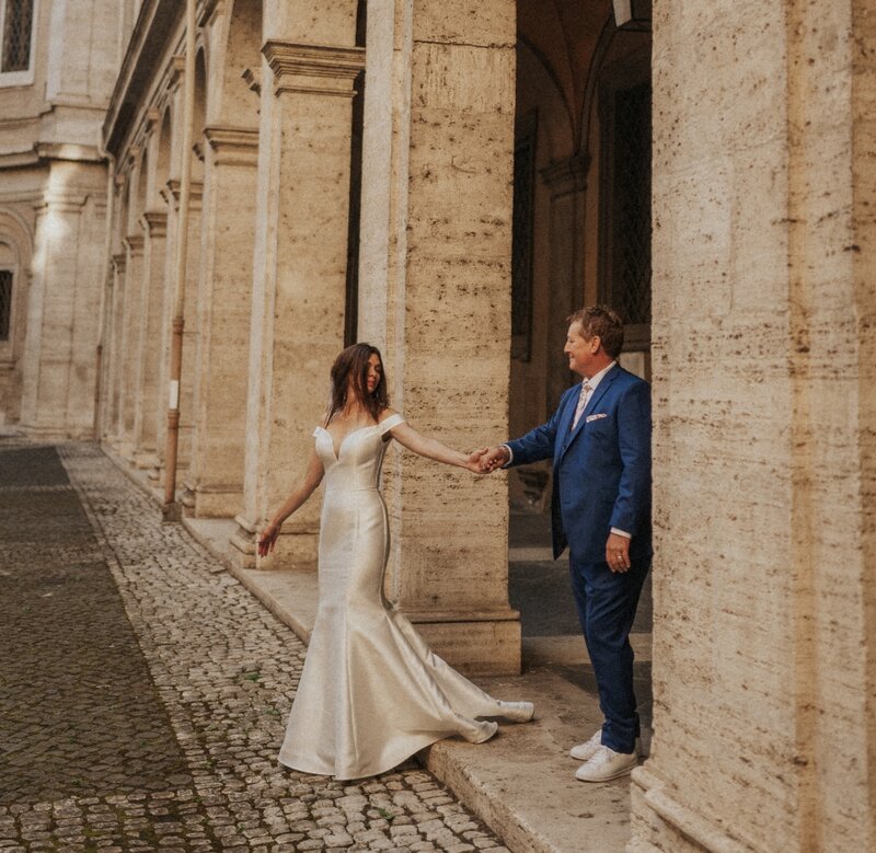 A couple holding hands and walking out of a building in Rome