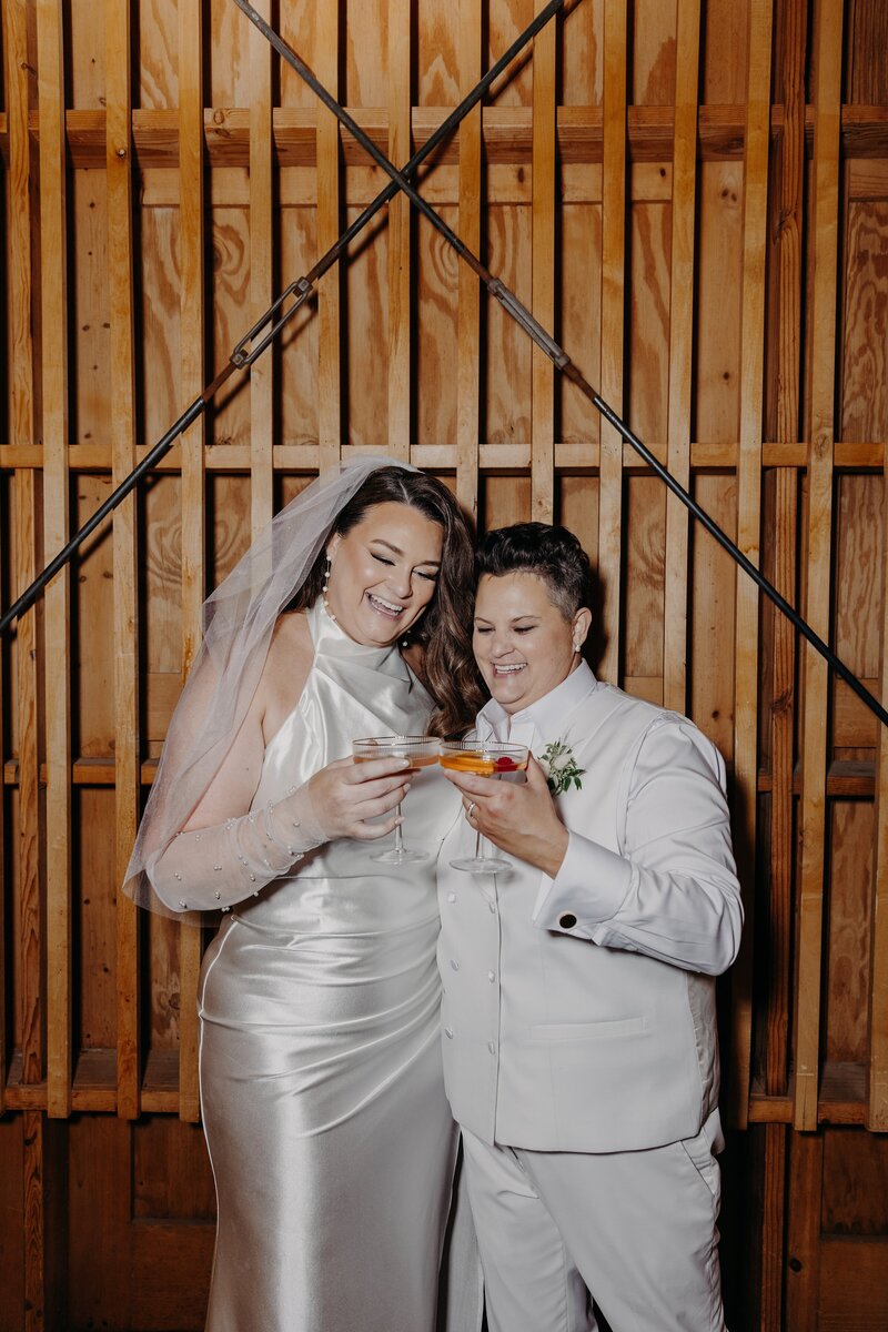 two brides smile and clink glasses