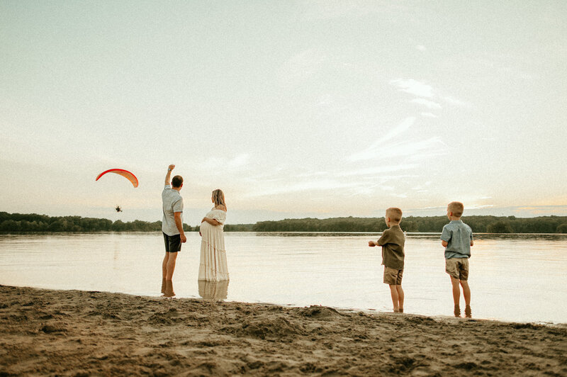 family on beach waving at parachute